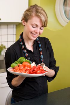 A female in the kitchen looking down on a tasty plate of vegetables - Shallow depth of feild is used to isolate the womans face.