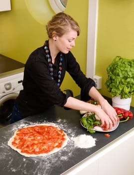 A young female making an italian style pizza at home in her apartment kitchen.