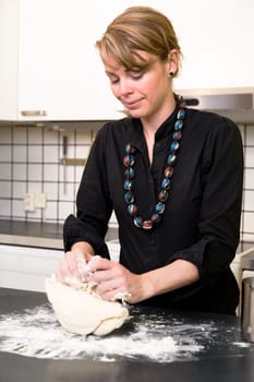 A young woman makes bread on the counter at home in the kitchen.