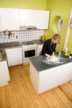 A young woman makes bread on the counter at home in the kitchen.