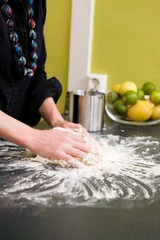 A young woman makes bread on the counter at home in the kitchen.