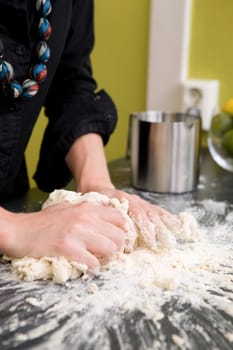 A young woman makes bread on the counter at home in the kitchen.