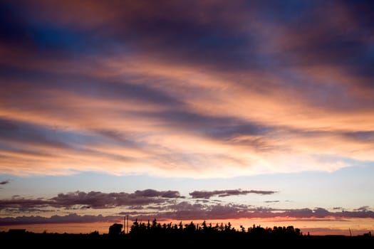 A prairie farm against a dramatic sunset