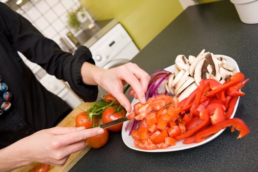 A vegetable platter is being prepared for a pizza.