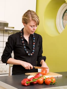 A female cutting tomatoes in her apartment kitchen.