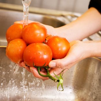 A detail image of washing tomatoes at home in the sink.