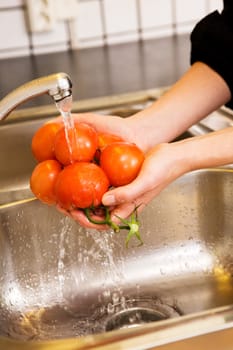 A detail image of washing tomatoes at home in the sink.