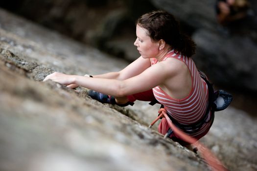 A female climber on a steep rock face.  Shallow depth of field is used to isolated the climber.