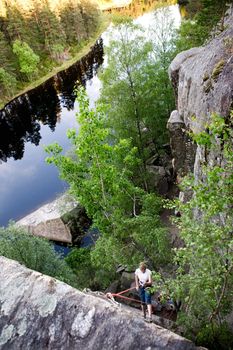 A female climber, repelling down a steep rock face (crag)