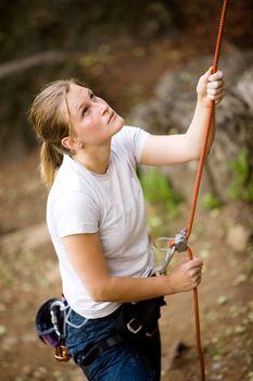 A female belaying a male on a steep rock face.  Shallow depth of field has been used to isolated the belayer, with focus on the eyes and head.