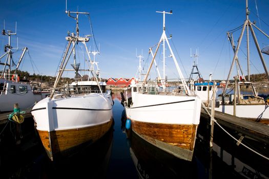 A number of fishing boats sit at dock on a warm summer day.