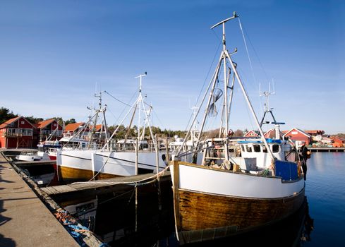 A number of fishing boats sit at dock on a warm summer day.