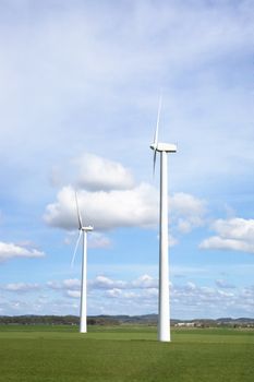 Windmill on a flat landsacpe capturing engergy against a blue sky