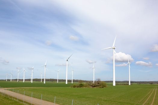 Windmill on a flat landsacpe capturing engergy against a blue sky