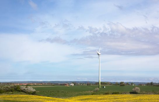 Windmill on a flat landsacpe capturing engergy against a blue sky