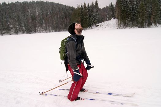 A cross country skiier looking like he is very tired. Humorous image.