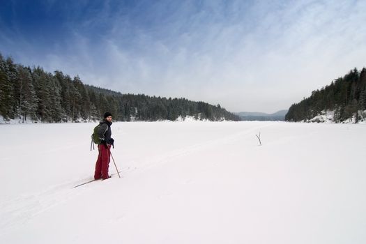 A cross country skiier out on a refreshing trip over a frozen lake.