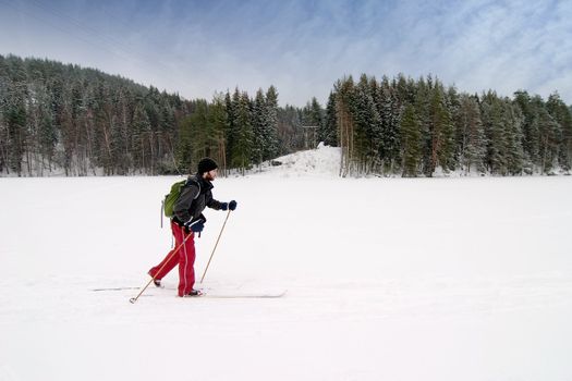 A cross country skier out on a refreshing trip over a frozen lake.