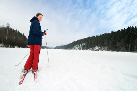 A cross country skiier out on a refreshing trip over a frozen lake.