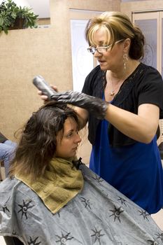 A hairdresser working on a clients hair color at the salon.