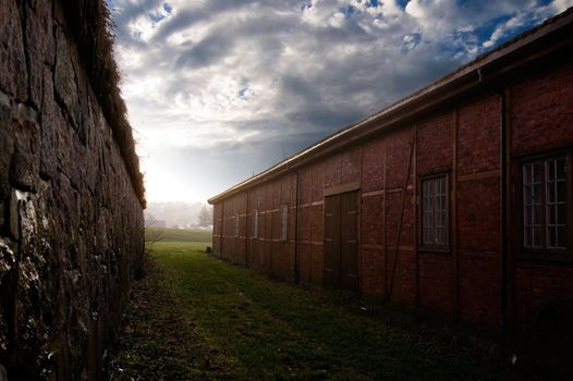 A small alleyway between two historical buildings leading out into light.