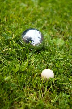 Bocce balls sitting in the green grass, close to the target. -shallow depth of field.-