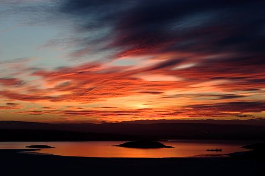 A golden sunset going down behind a hill over a frozen lake - fjord.  Oslo fjord in March.