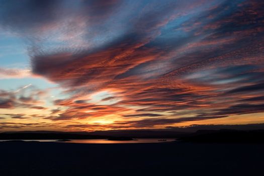 A golden sunset going down behind a hill over a frozen lake - fjord.  Oslo fjord in March.