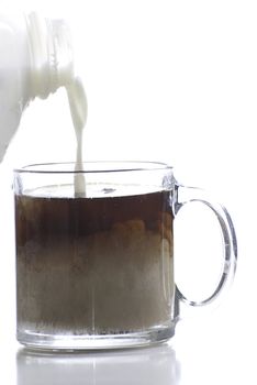 Cream being added to a cup of coffee, shot a against a white background