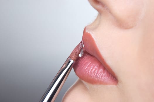 applying liquid gloss at the lips, moisturizing them