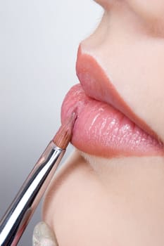 applying liquid gloss at the lips, moisturizing them