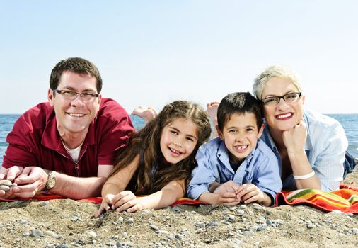 Happy family laying on towel at sandy beach