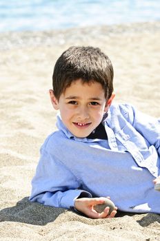 Portrait of young boy laying on sand at the beach