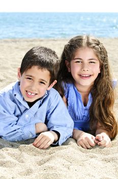 Portrait of brother and sister laying on sand at the beach
