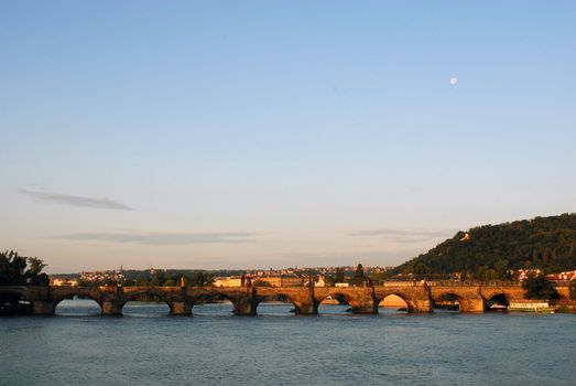 Landscape at dusk with the moon over a bridge. Prague
