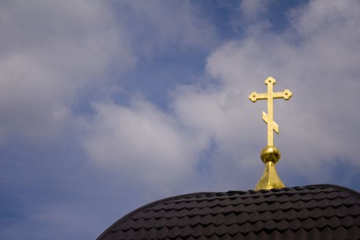 Detail of a golden cross on the roof of a cathedral