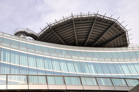 A modern office building facade made of steel and glass with a round construction on top