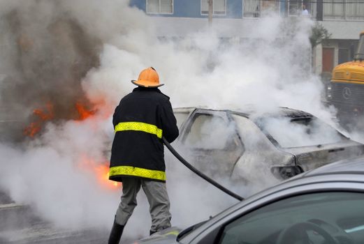 Car fire of a Citroen Xsara being extinguished by a firefighter at the corner of Concepci�n del Uruguay and Almer�a. Montevideo, Uruguay.