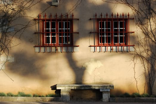 a bench under two barred windows