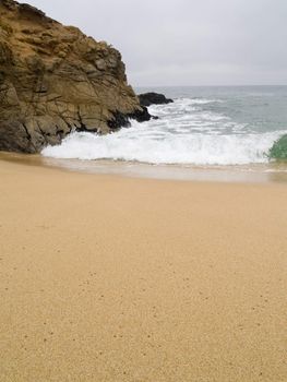 Small, cold waves crashing against a rock.