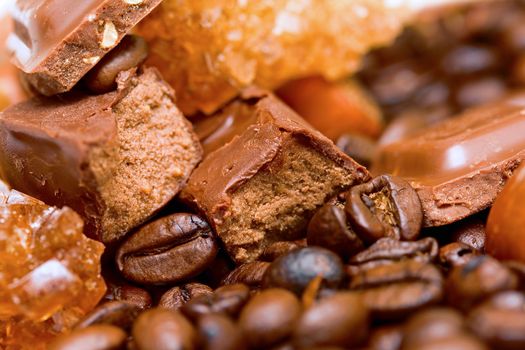 Coffee beans, delicious chocolate and hazel nuts close up