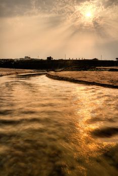 Sunset on river in yellow color with building silhouette.