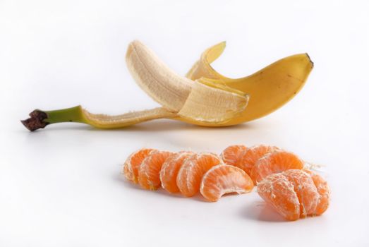 Peeled banana and juicy tangerine slices on white background