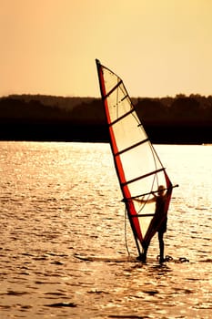 Silhouette of a windsurfing sail in the sunset