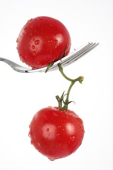 two tomatoes dangling from a fork