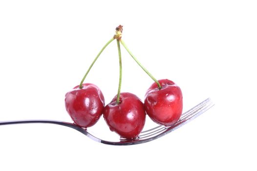 three cherries on a fork over white background