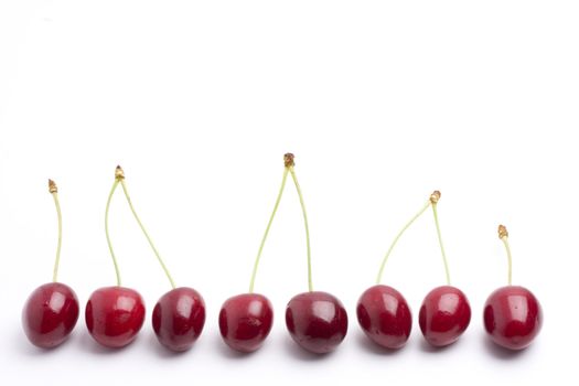 row of red cherries on white background