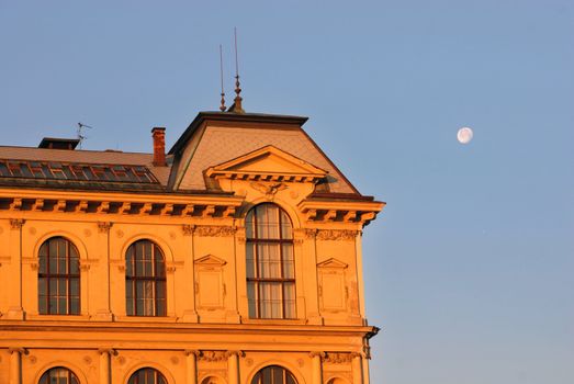 Upper part of a Prague building under a moonlit sky