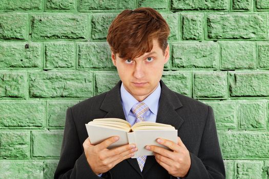 Person reads a book on the background of the stone wall