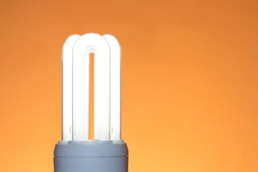 Energy saving compact fluorescent lightbulb isolated on ginger background